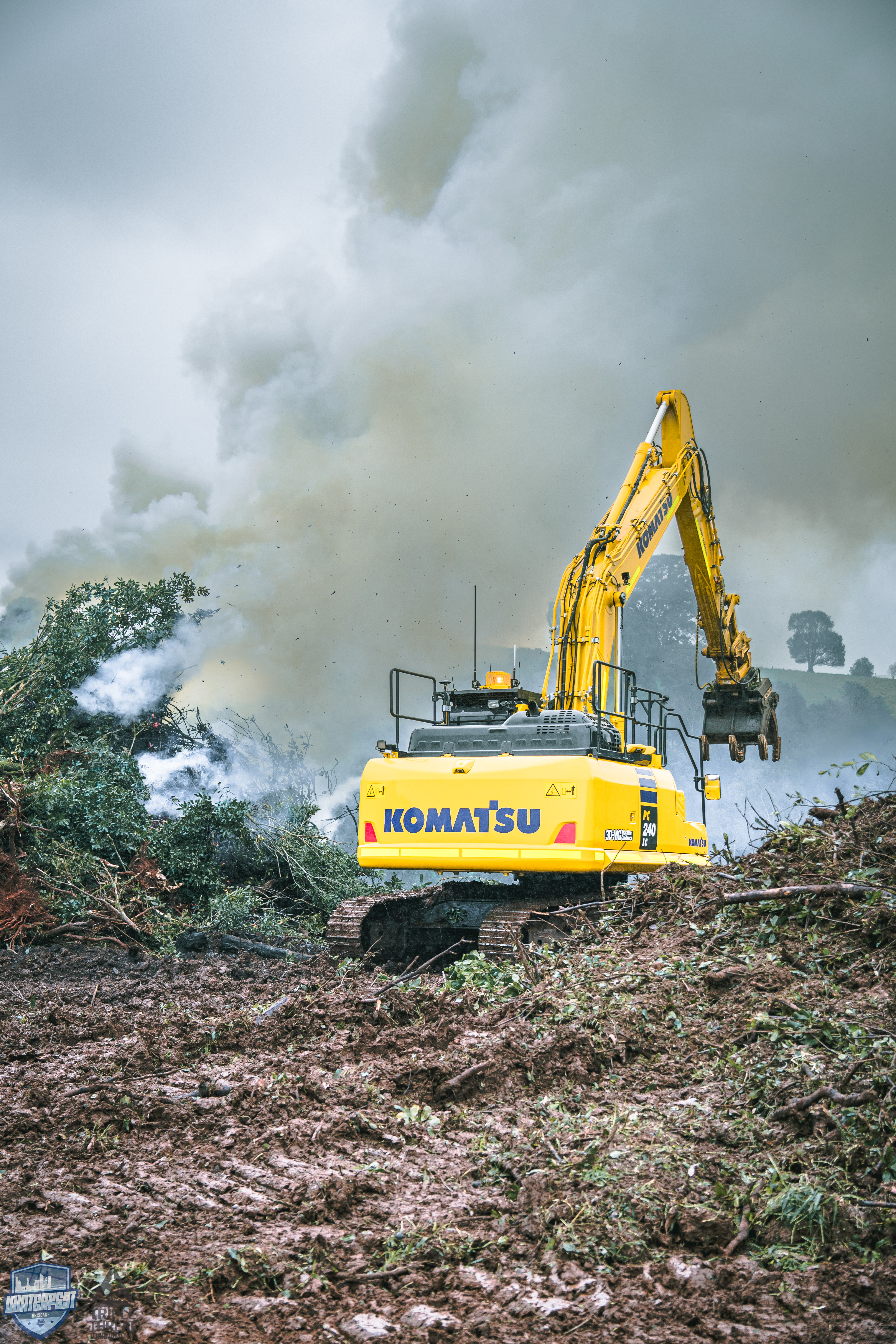 Excavator clearing vegetation with smoke